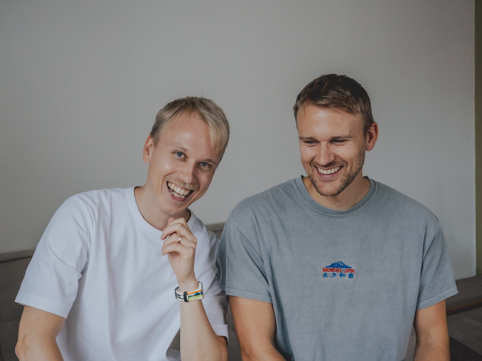 Max and Adam, who run Skriveriet, laughing together on a sofa